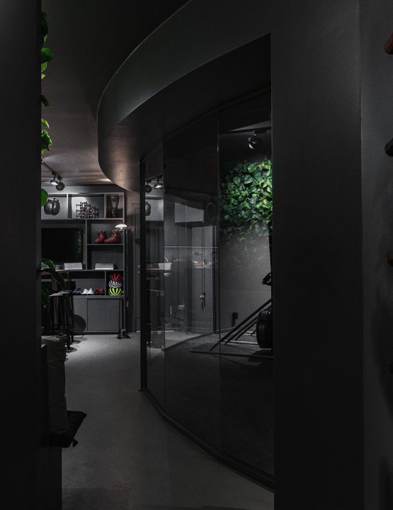 Elegant loungeområde avskilt med helglasväggar, reflexer av bil i bakgrunden.