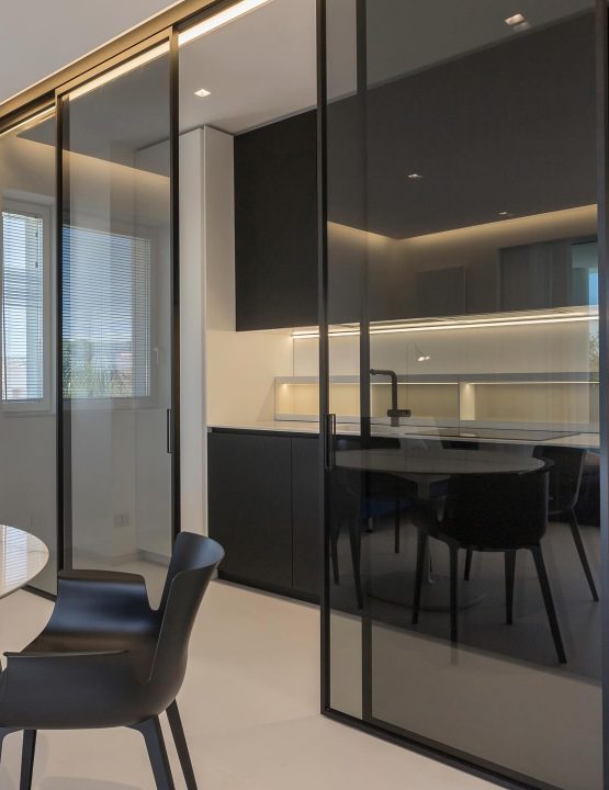 Modern skjutbar glasvägg från Albed som skiljer kök från matsal i ett stilrent och minimalistiskt hem